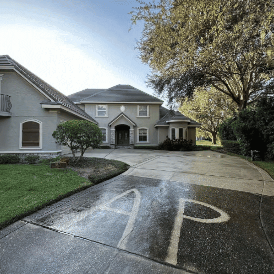 Luxury home with landscaped yard and driveway featuring "AP" marking in wet cement.