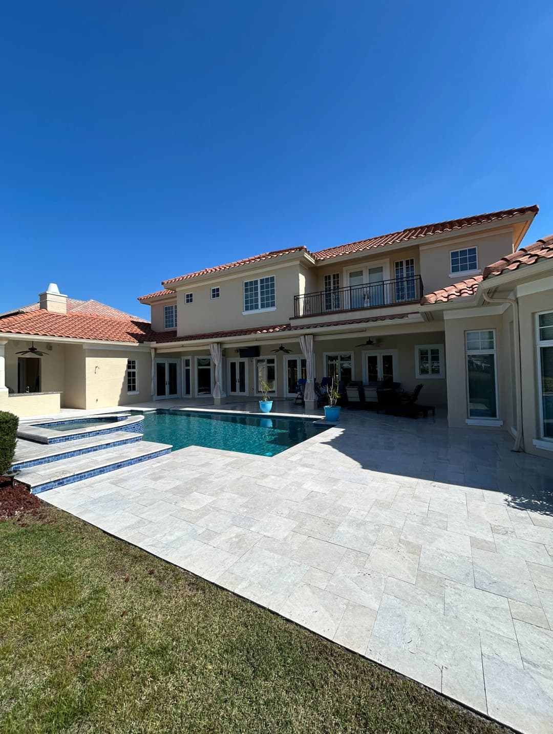 Luxury home with pool and patio under clear blue sky, showcasing elegant architecture.