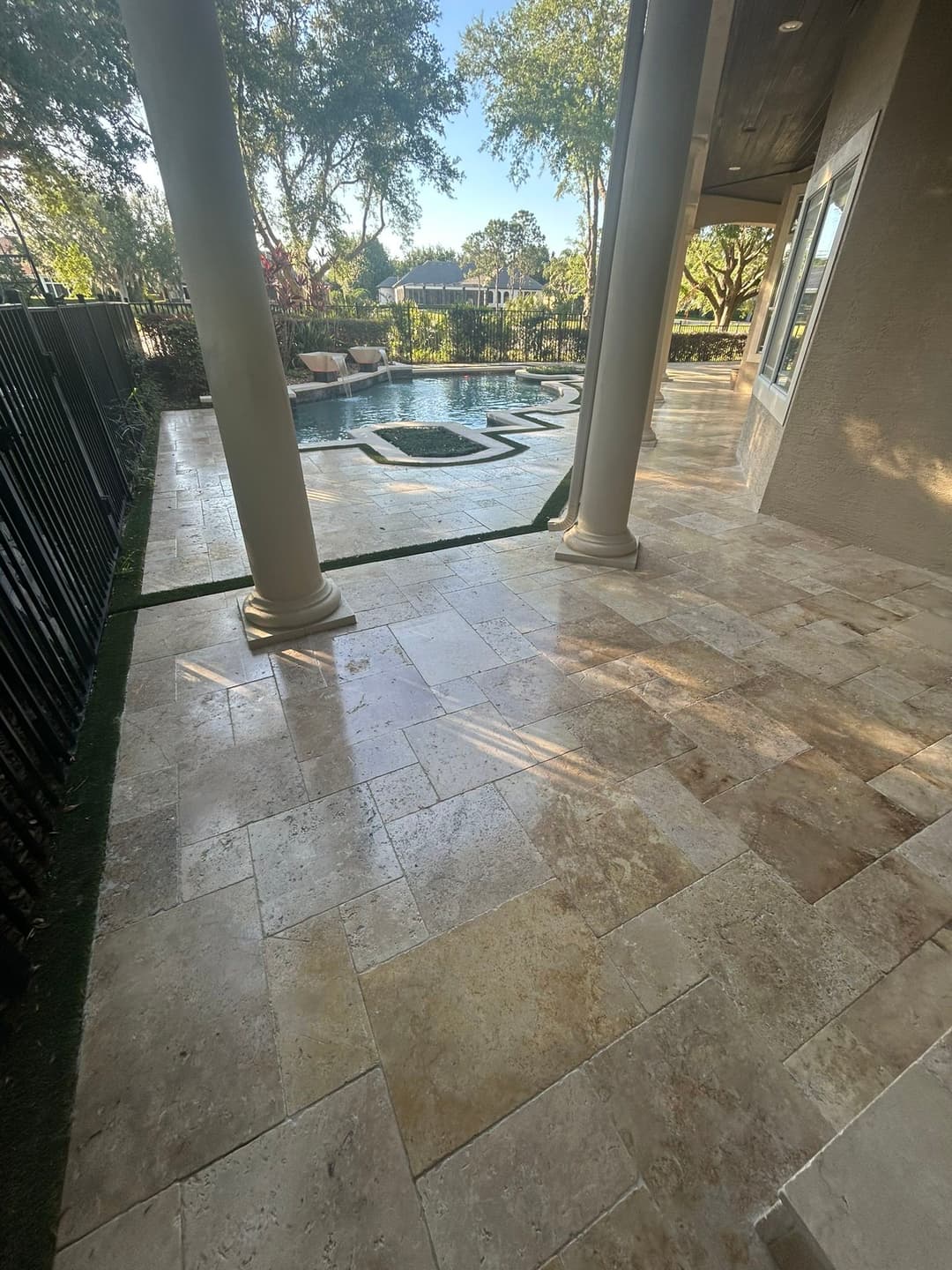 Modern outdoor patio with polished stone tiles, pool, and scenic landscaping views.